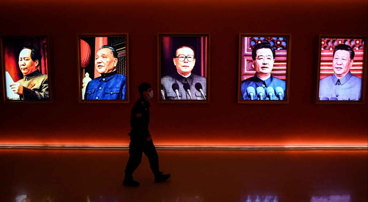 A man walks past portraits of Chinese leaders